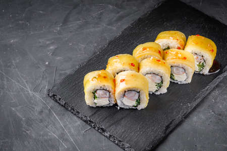 delicious sushi rolls on a black stone background.