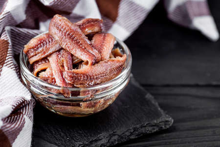 canned anchovy fillet on a black wooden rustic background.