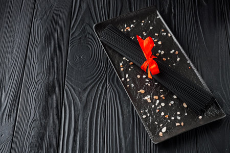 delicious black spaghetti pasta on a black rustic wooden background.