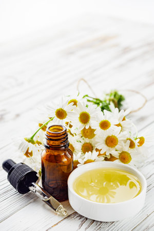 aromatic chamomile essential oil on a white wooden rustic background.の写真素材