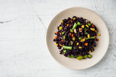 delicious black rice with vegetables on a white background.の写真素材
