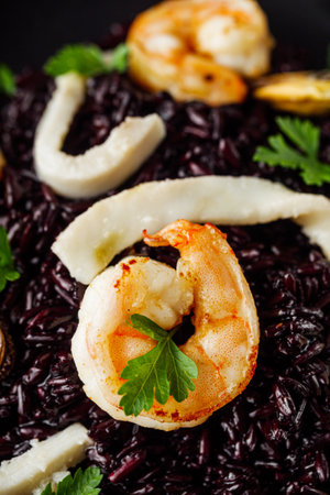 delicious black rice with shrimps and seafood on a black wooden rustic background.の写真素材