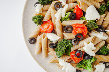 delicious penne wheat pasta with tomatoes, broccoli and mozzarella on a white background.