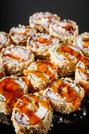 hot sushi roll tempura with eel shrimp crab salmon cream cheese cucumber avocado unagi on a black mirror background.の写真素材