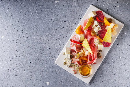 a tray of assorted meat and cheese on a light stone background.の写真素材