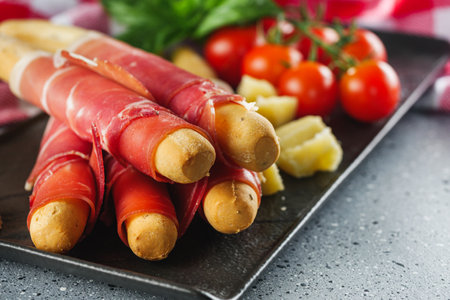 crispy grissini with prosciutto on a light stone background.の写真素材