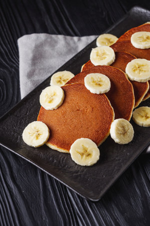 fresh tasty pancakes with banana and condensed milk on a black rustic background.の写真素材