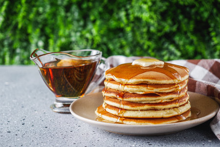 fresh tasty pancakes with maple syrup on a light stone background.