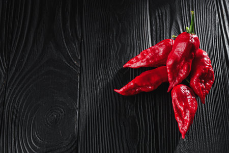 fresh red extra hot bhut jholokiya pepper on black wooden rustic background.