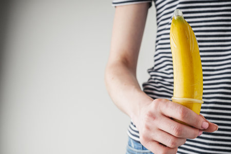 young girl putting a condom on a banana contraception concept.の写真素材