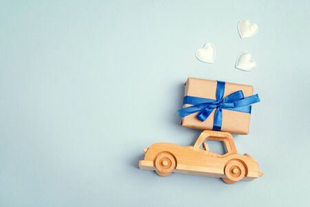Wooden toy car with a gift box on the roof on blue background. Copy space for text, top view. Fathers day background.の写真素材