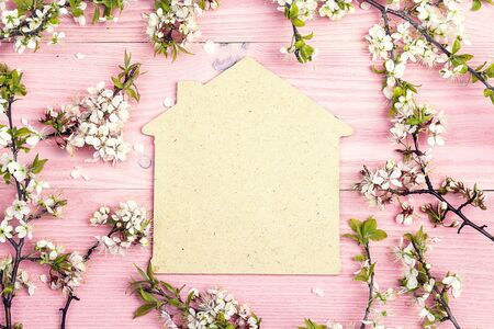 Symbol of the house with blossoming apple tree branches on pink wooden background. Copy space. Spring flowering branch.の写真素材