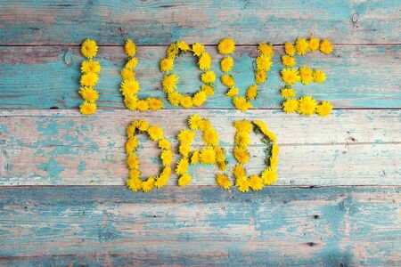 Fathers day background with letters from yellow dandelions on old turquoise wooden background. Copy space. Happy fathers day concept.の写真素材