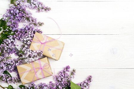 Lilac flowers with gift boxes on white wooden background. Top view, flat lay, copy space.の写真素材