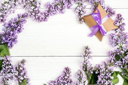 Frame of  lilac flowers with gift box on white wooden background. Top view, flat lay, copy space.の写真素材