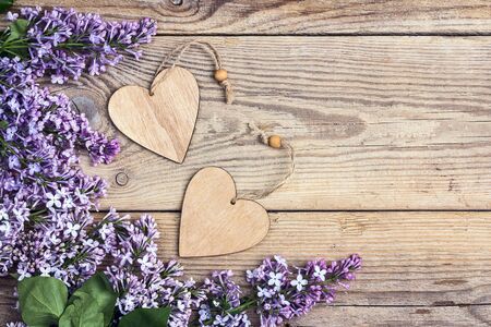 Lilac flowers with decorative hearts on old wooden background. Top view, copy space.の写真素材