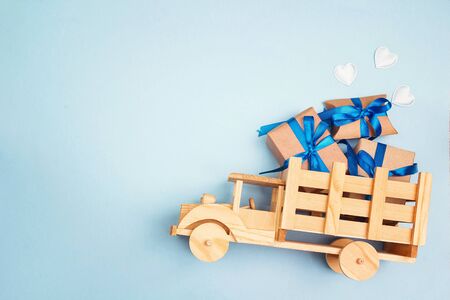 Wooden toy truck with gift box in the back on blue background with cipy space. Top view, flat lay.の写真素材