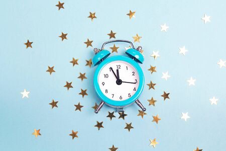 Blue alarm clock with small golden stars. Time for magical events.の写真素材