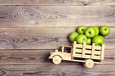 Toy wooden truck with green apples in the back on wooden  background. Place for text, top view.の写真素材