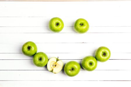 Smiling face of green apples on white wooden table. Apple emoticon. Top view.の写真素材