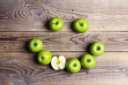 Smiling face of green apples on a wooden table. Apple emoticon. Top view.の写真素材