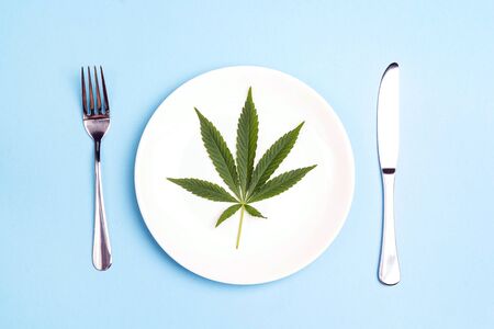 Medical concept table setting with cannabis leaf on blue background.