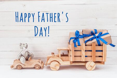 Father's Day card. Wooden car with toy bear and wooden truck with gifts. Happy Father's Day.の写真素材