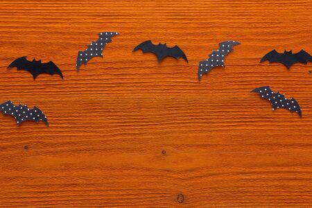 Paper bats on a orange wooden background. Halloween background. Space for text.