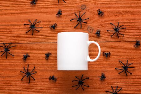 White coffee mug with decorative spiders on orange background. Space for text or design.の写真素材