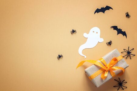 Halloween background with gift box, decorative ghost, spiders and bats on orange background. Blank space for text. Festive  concept.の写真素材
