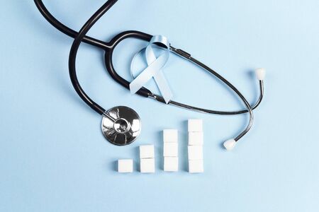 Blue ribbon awareness as symbol of diabetes with stethoscope and sugar chart on a blue background/  World diabetes day concept. Top view.の写真素材