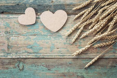 Background with ears of wheat and wooden hearts on old blue boards. Space for text.