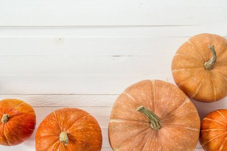 Background with several pumpkins on white wooden boards. Space for text. View from above.