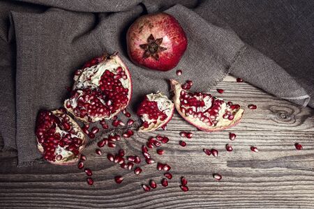 Still life with fresh juicy pomegranate - whole and cut, on sackcloth on on rustic wooden table.の写真素材