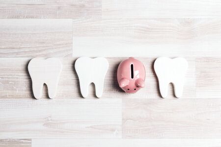 Pink piggy bank with teeth on a light wooden background. Investing in dental health care.の写真素材