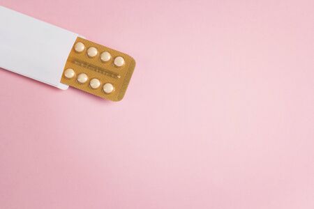 Female oral contraceptive pills blister with copy space on pink background. Women contraceptive...