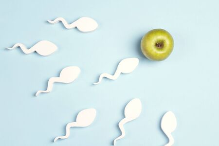 Sperm cells moving towards the green apple egg on a blue background.の写真素材