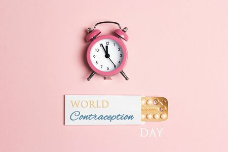 World Contraception Day Poster; September 26. Female oral contraceptive pills blister with alarm clock on pink background.の写真素材