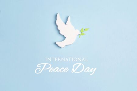 World Peace Day greeting card. Dove of peace with olive branch and text on a blue background.の写真素材