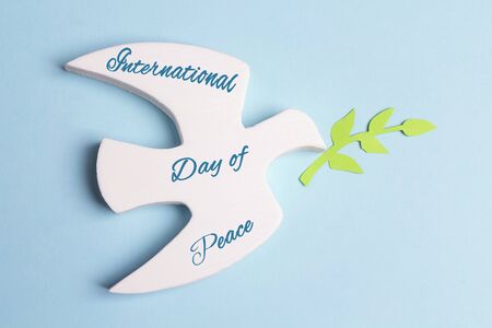 World Peace Day greeting card. Dove of peace with olive branch and text on a blue background.の写真素材