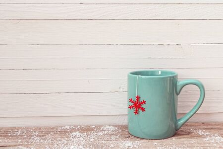 Blue Christmas tea mug with red snowflake on wooden table. Copy space.の写真素材