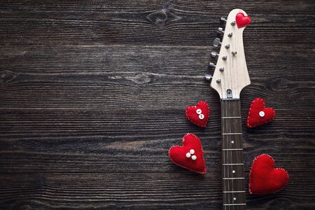 Neck Electric Guitar with hearts on a dark wooden background. Valentine's Day background. Space for...