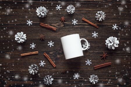 White coffee mug with pine cones, cinnamon sticks and star anise on dark wooden table.  Top view. Flat lay.の写真素材