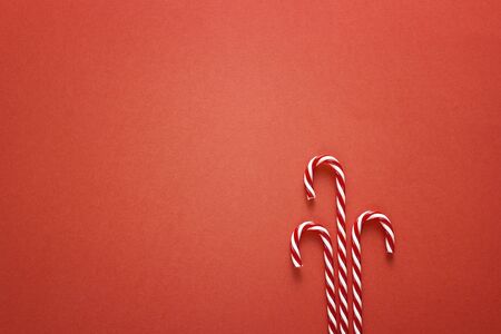 Red Christmas background with candy canes. Top view, flat lay. Copy space for text. Christmas minimalism.の写真素材
