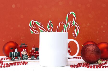 White coffee mug with candy canes and Christmas decorations on red background. Space for text or design.の写真素材
