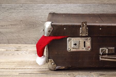 Vintage suitcase with santa hat on wooden rustic background. Christmas holiday concept.の写真素材