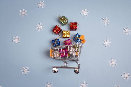 Shopping trolley with gift boxes on blue background. Christmas and New Year sale.の写真素材