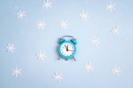 Winter alarm clock with snowflakes  on blue background. Time to celebrate.  Christmas timer. の写真素材