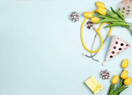 Festive  background with stethoscope, yellow tulips and festive caps with copy space for text. National Doctor's or nurse day.の写真素材