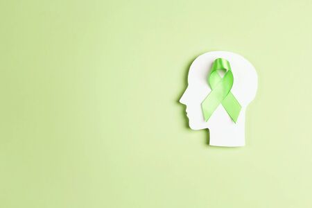 World mental health day concept. Green awareness ribbon with brain symbol on a green background. Copy space for text.の写真素材